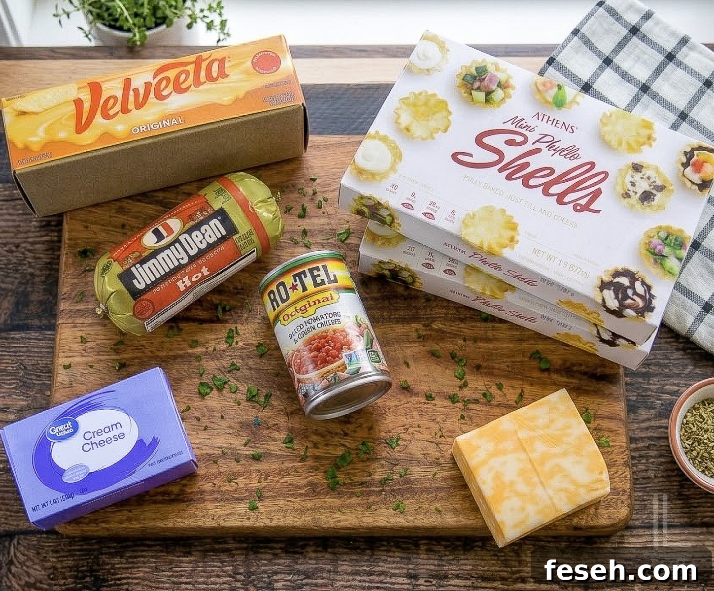 ingredients for cheesy sausage rotel cups, including phyllo shells, velveeta, rotel, colby jack cheese, and breakfast sausage.