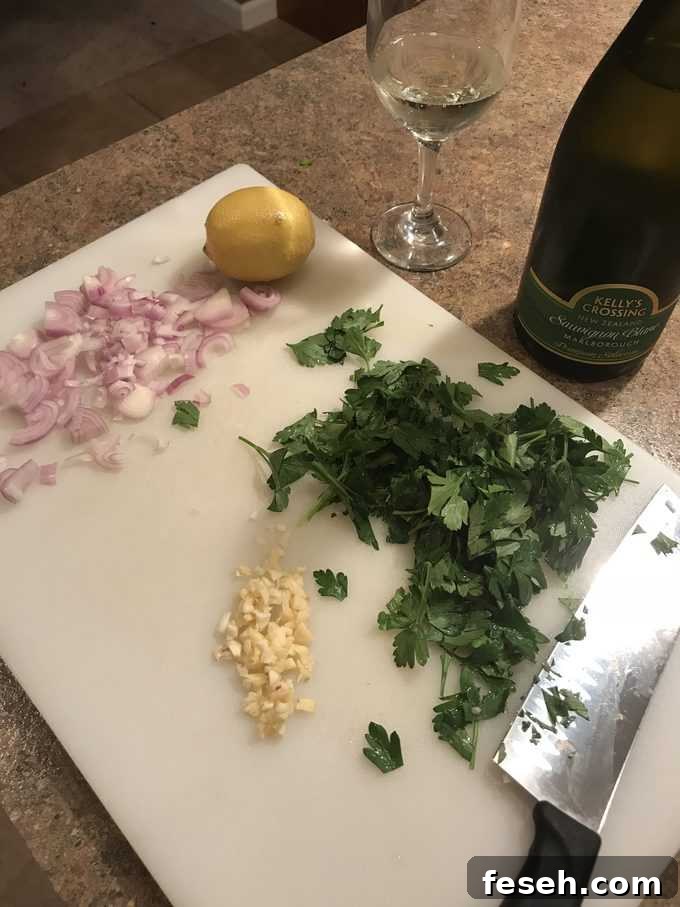 Prepping shallots, garlic, parsley, wine, lemon on cutting board for pan seared salmon.