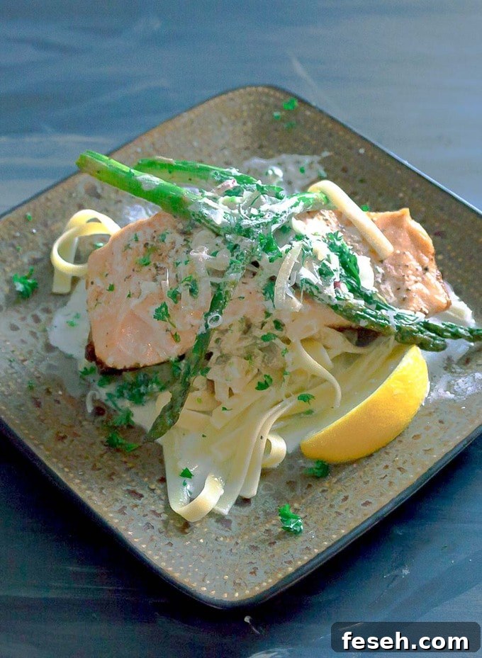Salmon with Garlic Cream Sauce on square plate with asparagus and pasta