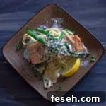 Pan Seared Salmon with Garlic Wine Cream Sauce over linquine on sqaure plate with 3 spears of roasted asparagus