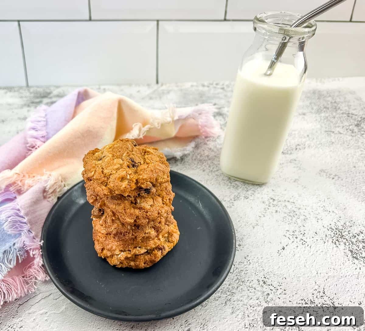 Oatmeal raisin cookies on a plate next to a glass of milk.