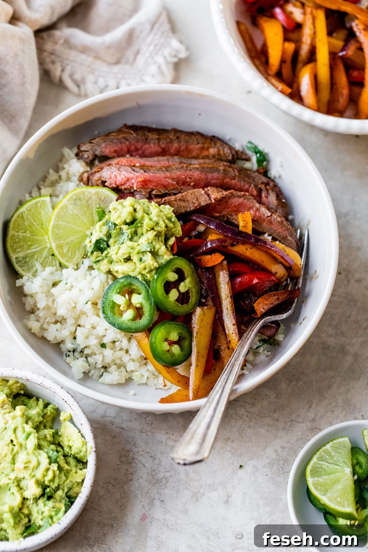 steak fajita bowl with cauliflower rice, flank steak, peppers, and guacamole