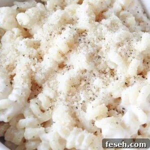 A bowl full of cottage cheese pasta sauce on chickpea pasta and topped with parmesan cheese and black pepper.