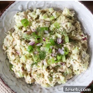 Cottage cheese tuna salad garnished with herbs and red onion in a bowl.