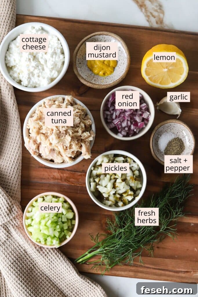 Ingredients for cottage cheese tuna salad on a wooden board with labels.