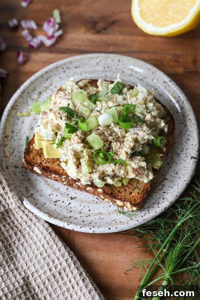 Cottage cheese tuna salad garnished with herbs and red onion on toast.
