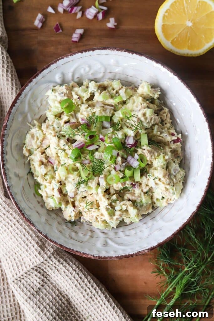 Cottage cheese tuna salad garnished with herbs and red onion in a bowl.