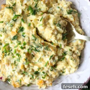 Cottage cheese egg salad in a bowl garnished with chives served with a spoon.