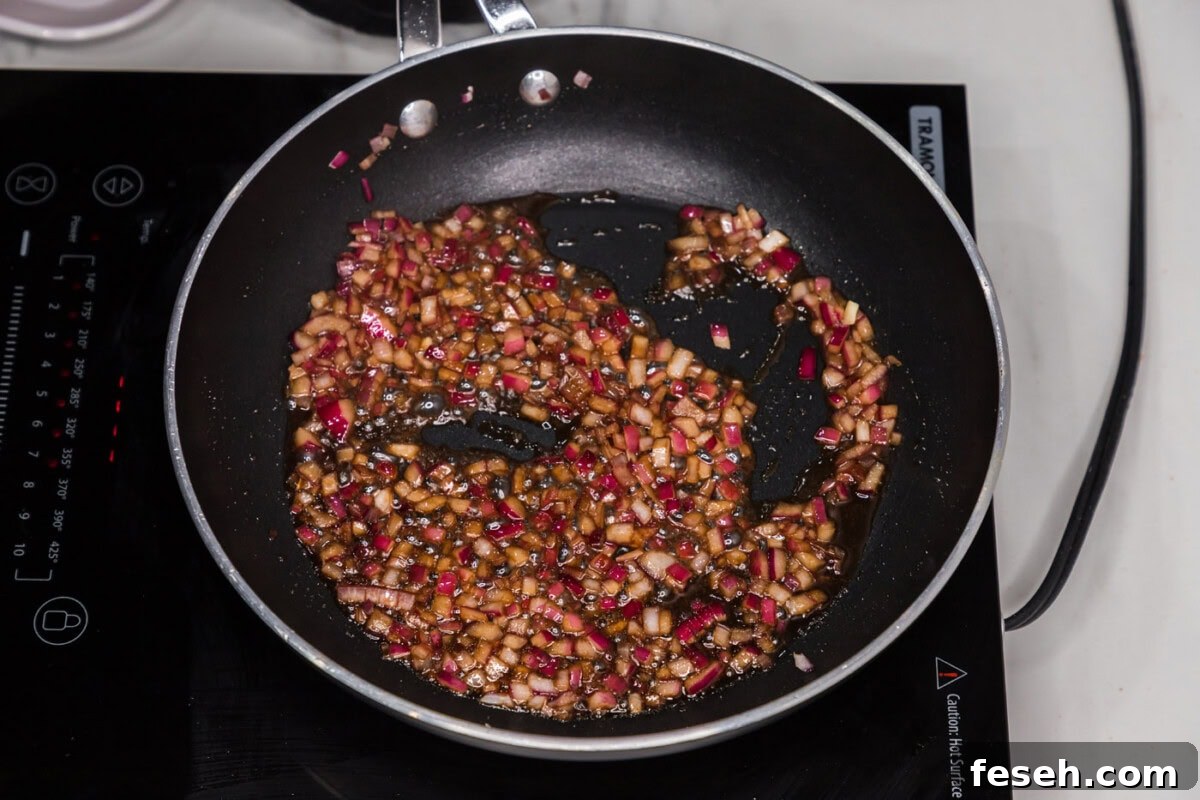 red onion sauteeing in olive oil in a skillet with liquid smoke and worcestershire sauce