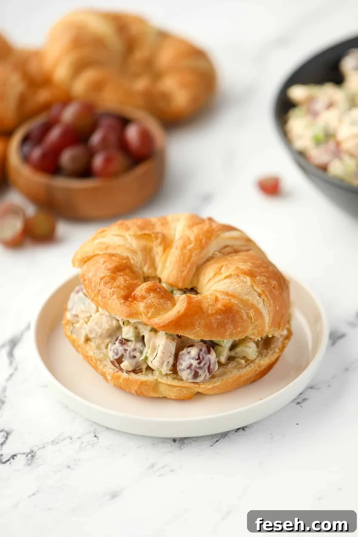 A croissant sliced in half and filled with chicken salad.