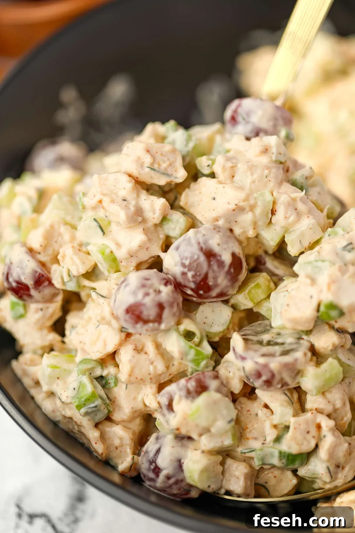 A close up of chicken salad dotted with red grapes.