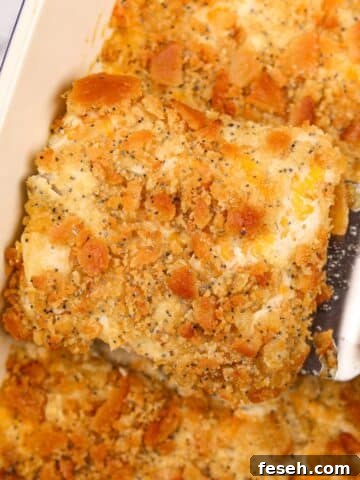 Lifting creamy chicken casserole from a baking dish using a spatula.