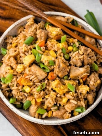 A bowl of chicken fried rice with chopsticks on the side.