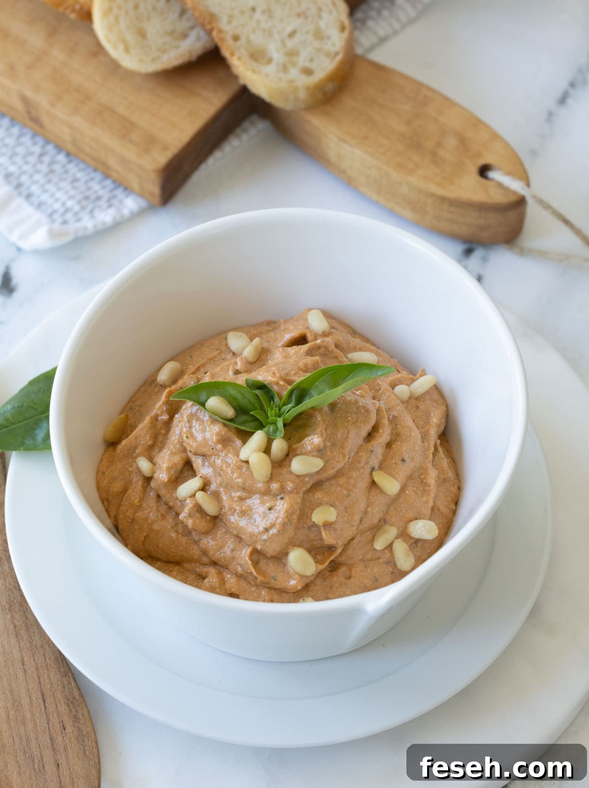 A white bowl of creamy whipped ricotta dip with sun-dried tomato pesto.