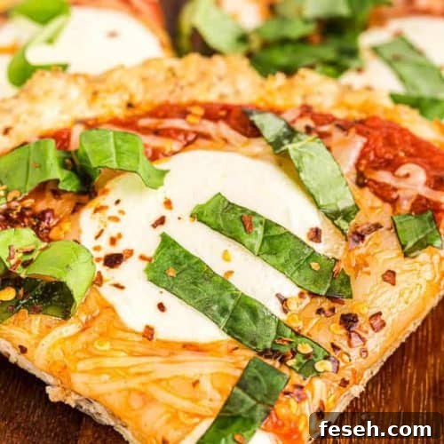 closeup of slice of keto chicken crust pizza covered with fresh basil