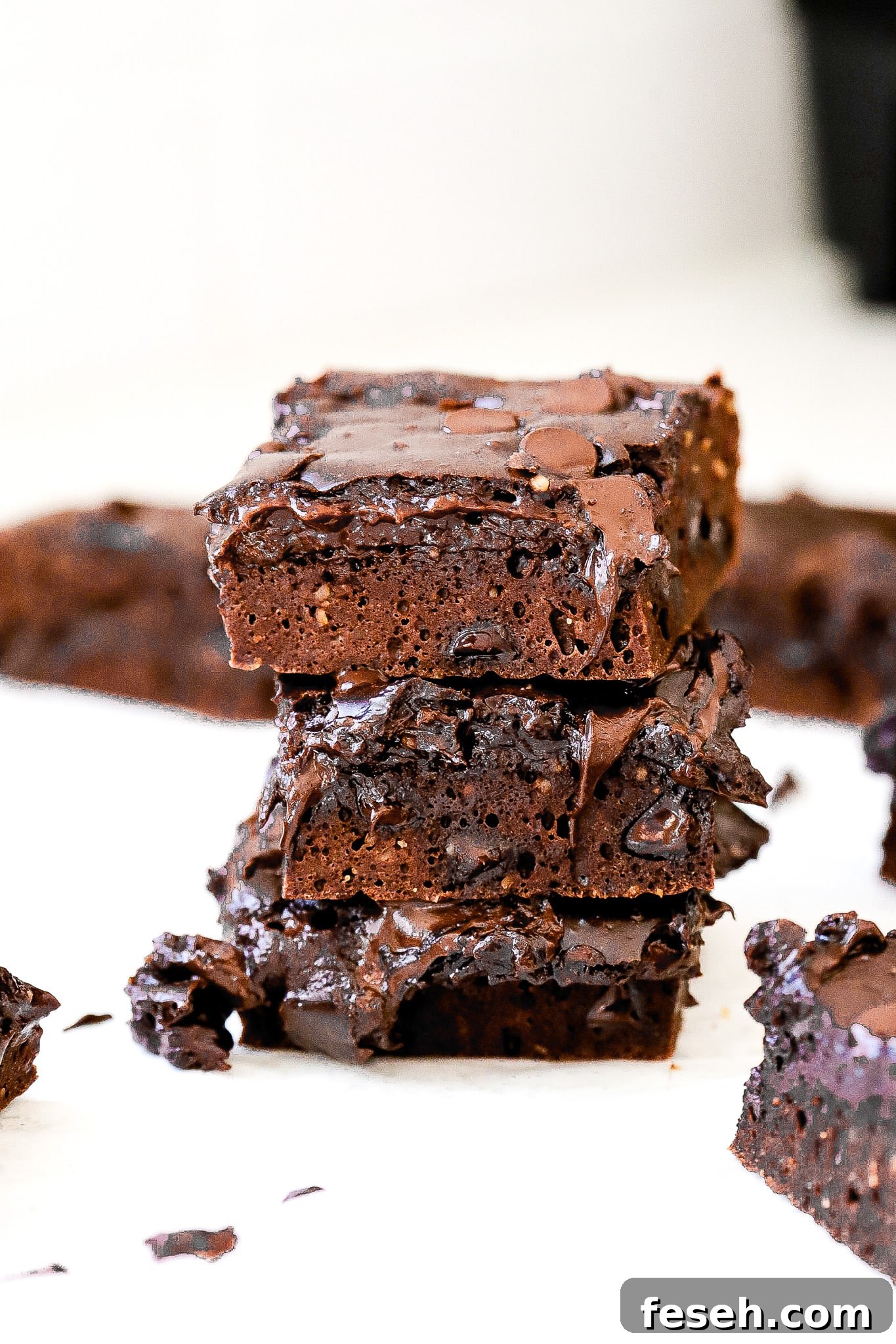 Side view of high protein brownies stacked on top of one another with more brownies in background.