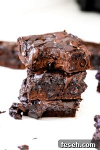 Side angle of bite shot of flourless fudge protein brownies stacked on top of one another.