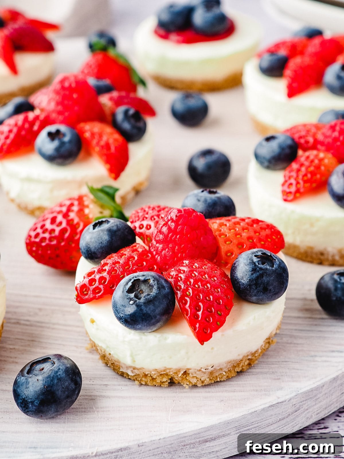 Cheesecakes on a platter with fresh fruit.