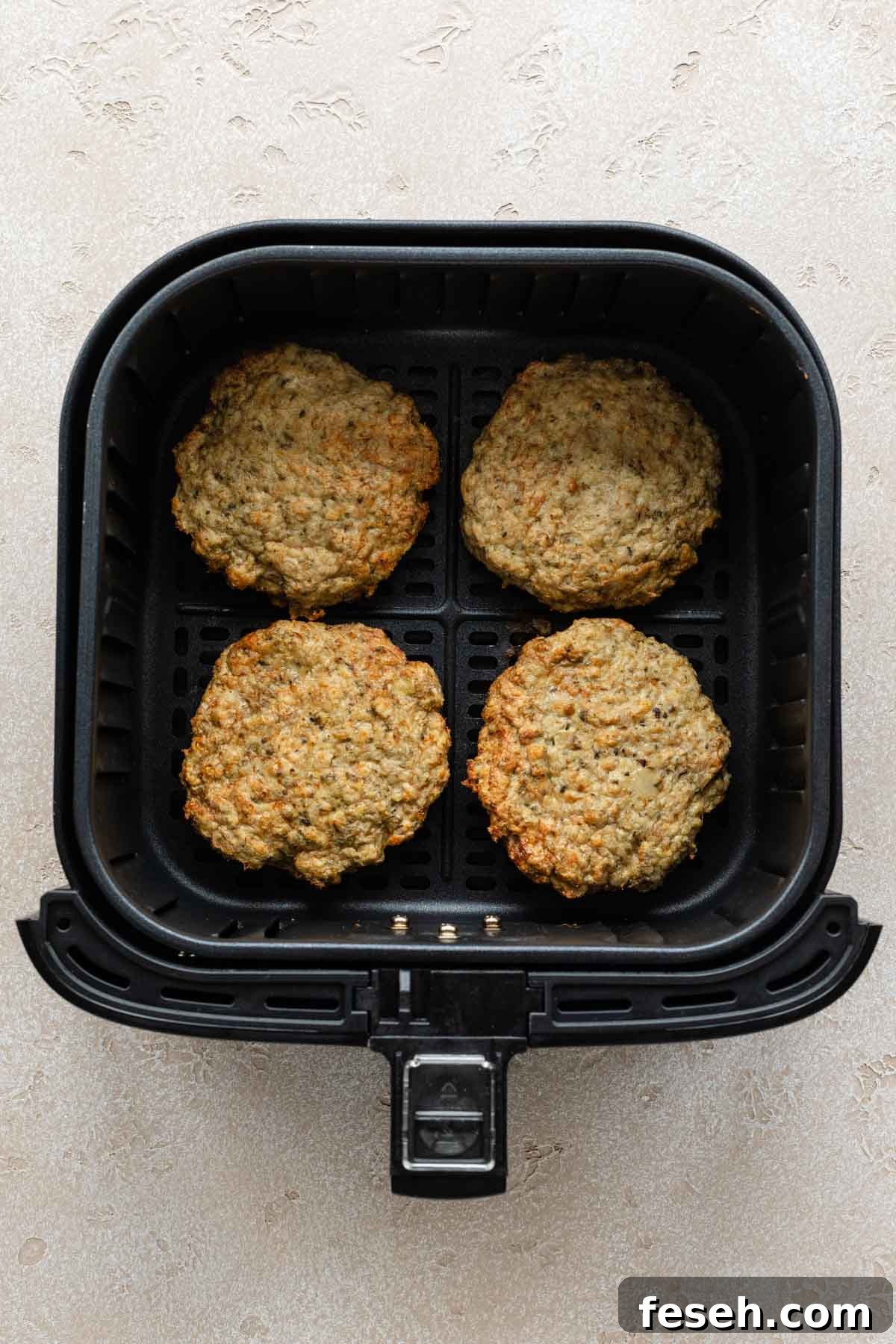 Four turkey burgers cooked in an air fryer basket.