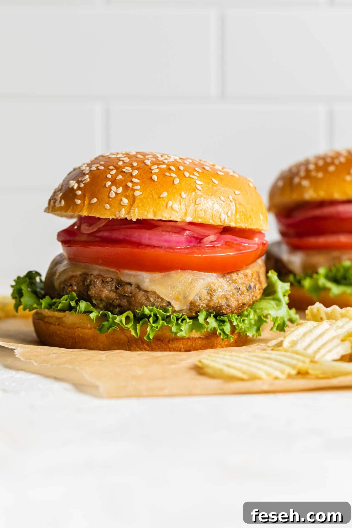 Up close side view of a turkey burger on a sheet of brown parchment paper.