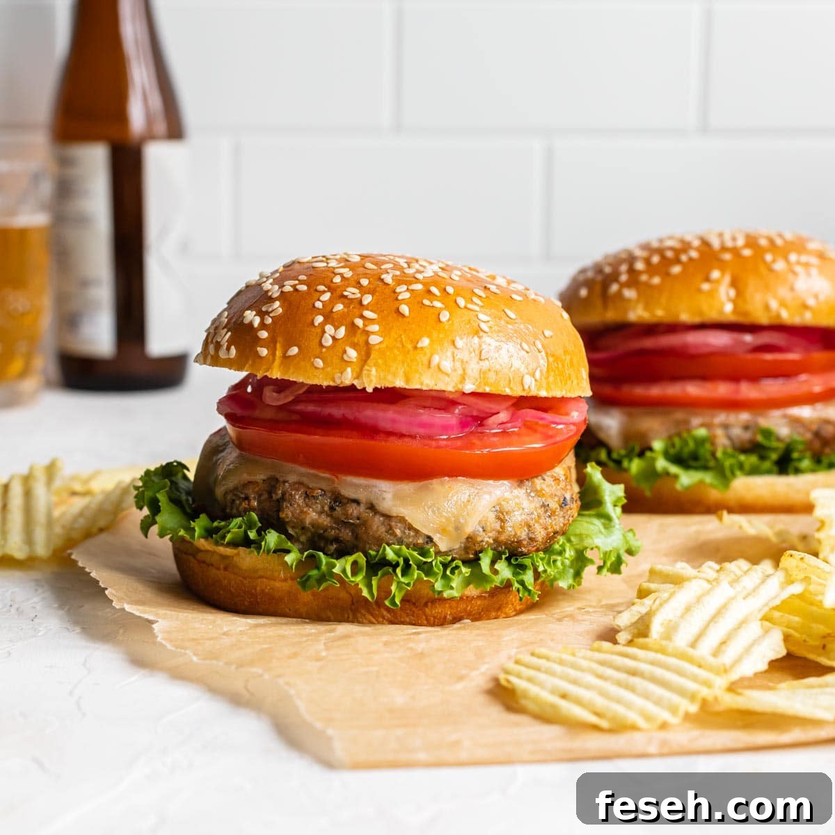 Air fryer turkey burgers arranged on a sheet of brown parchment paper with potato chips on the side.