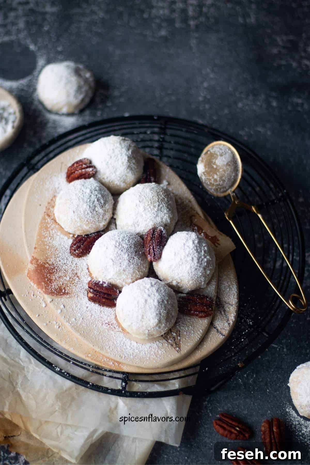 wedding cookies placed on a plate over a wire rack with pecans on top as garnishing