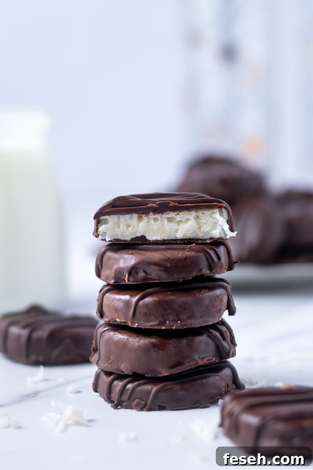 stack of chocolate candies with the top candy cut in half showing the coconut filling