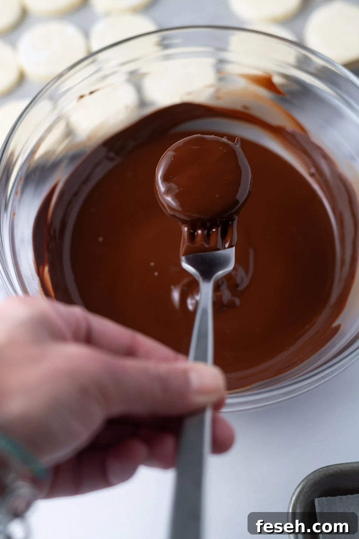 hand holding a fork with a candy dipped in chocolate