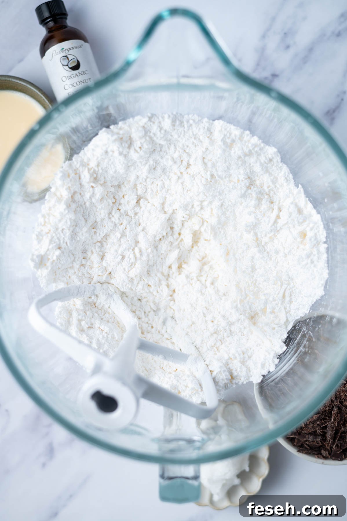 confectioners' sugar, butter and coconut mixed in a mixing bowl