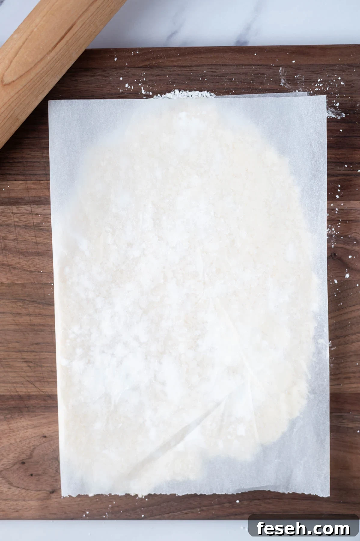 parchment paper over candy filling on a cutting board with a rolling pin