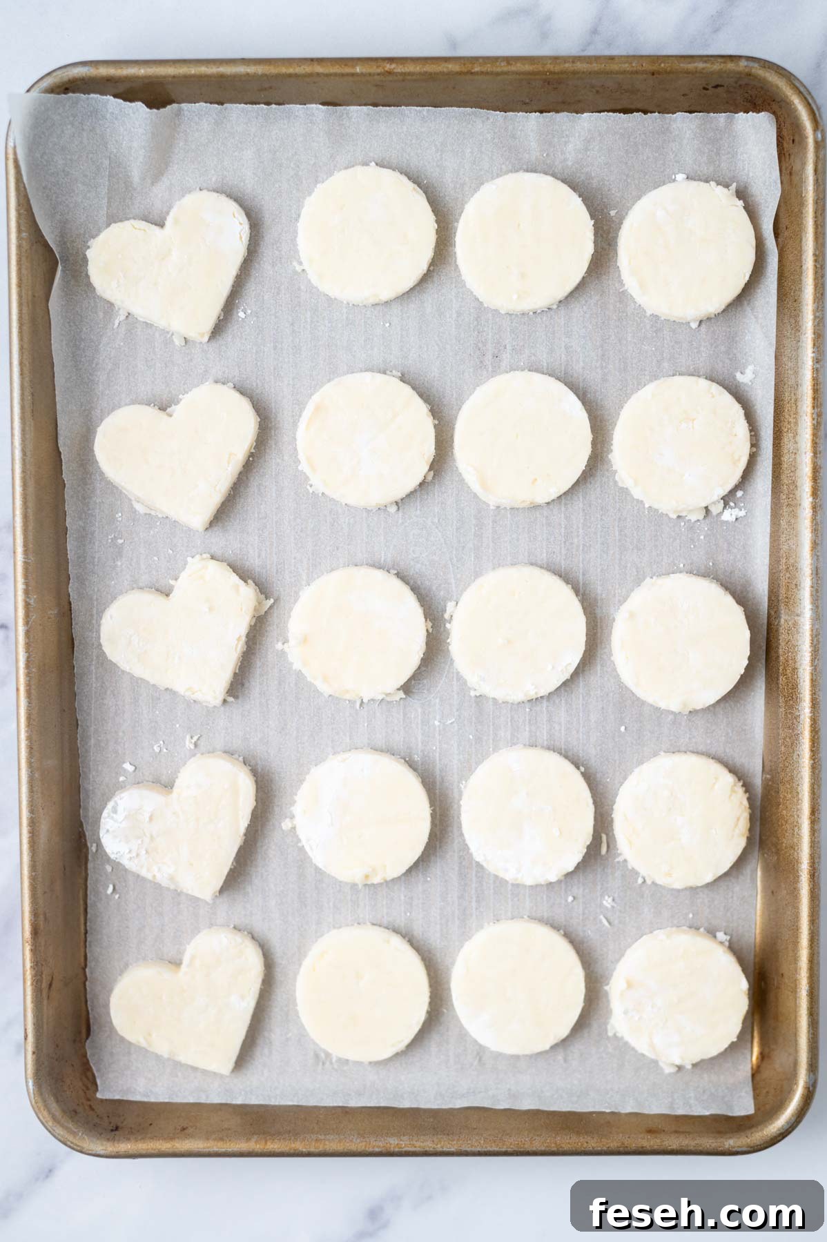 round and heart shaped coconut filling on a parchment lined baking pan