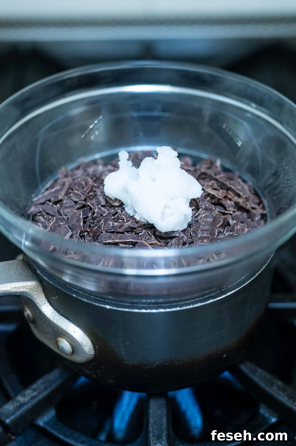 chopped chocolate and oil in a bowl atop a pot of water on the stove
