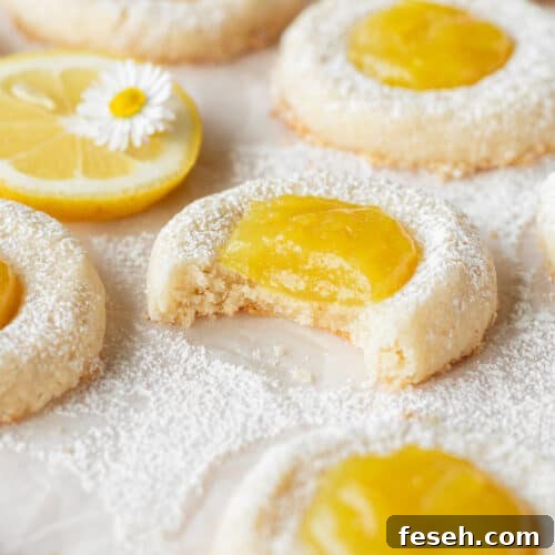 A bitten lemon curd cookie on a piece of parchment paper.