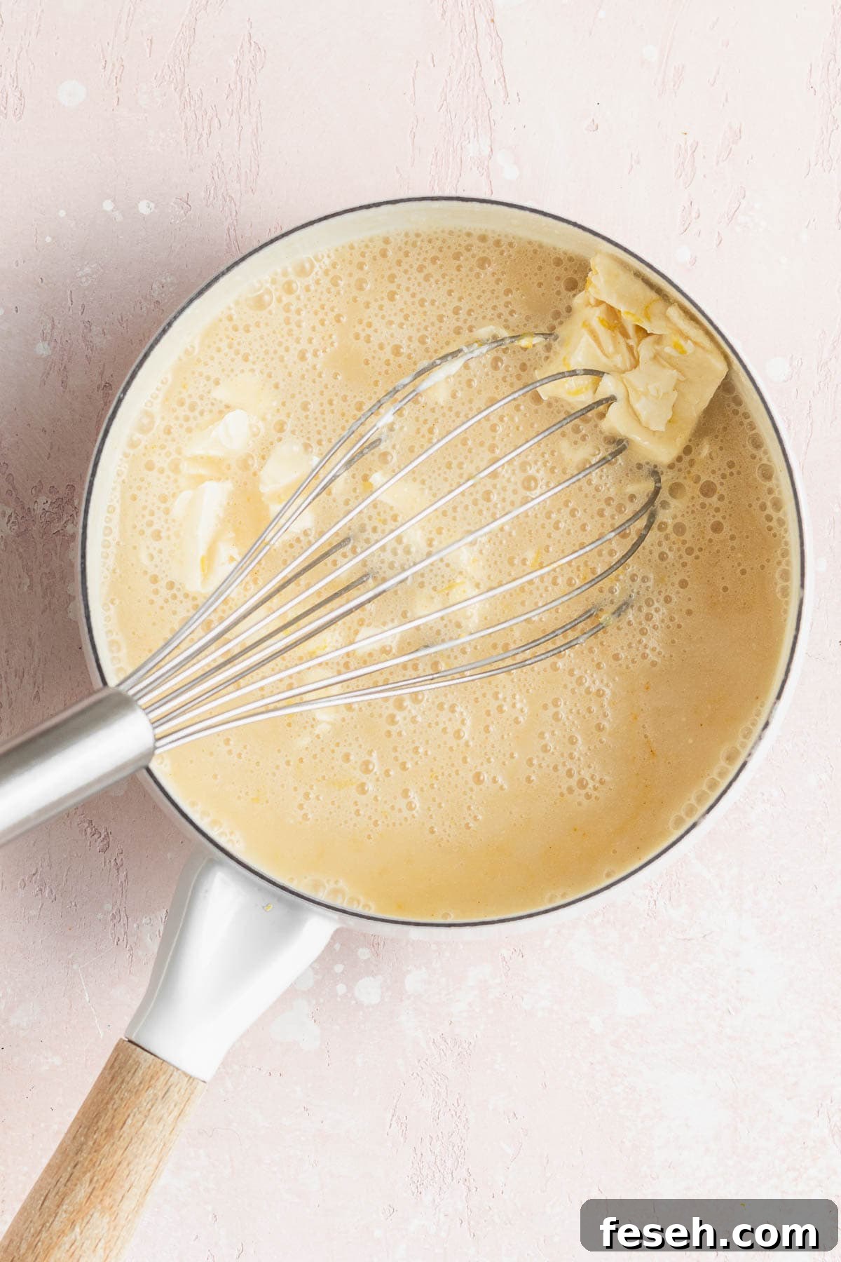 Whisking the butter into the warmed vegan lemon curd mixture in a saucepan.