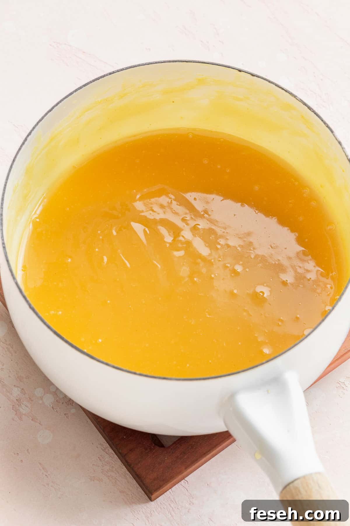 completed lemon curd in a sauce pan. it is bright yellow like the color of an egg yolk.