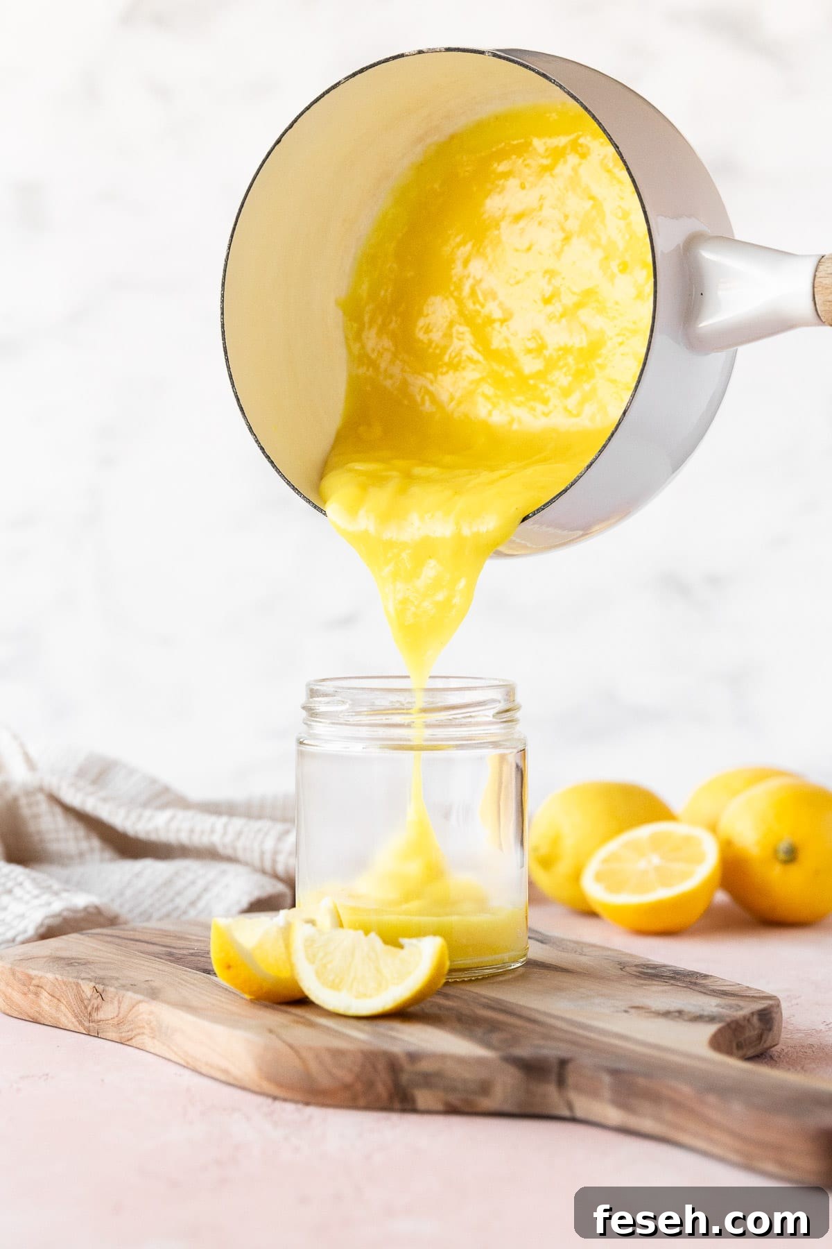Pouring the vegan lemon curd from a saucepan into a mason jar.