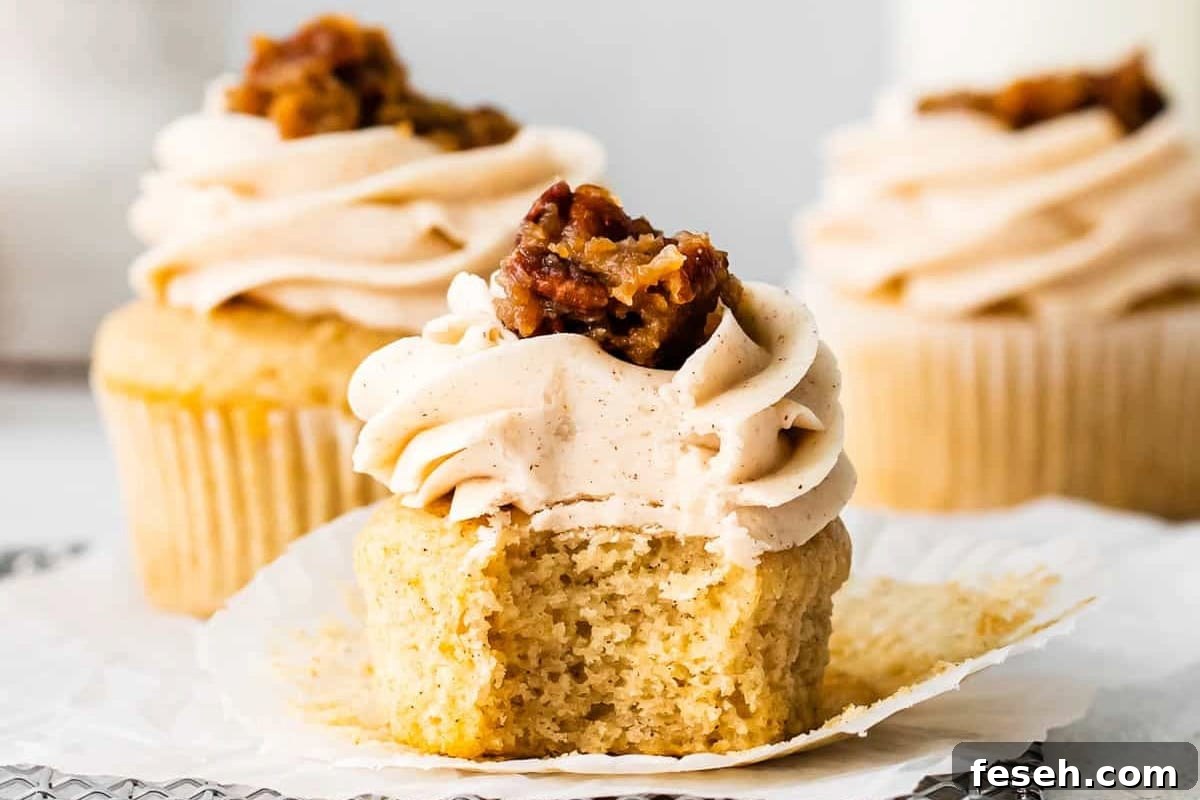 an unwrapped and bitten pecan pie cupcake on a wire rack.