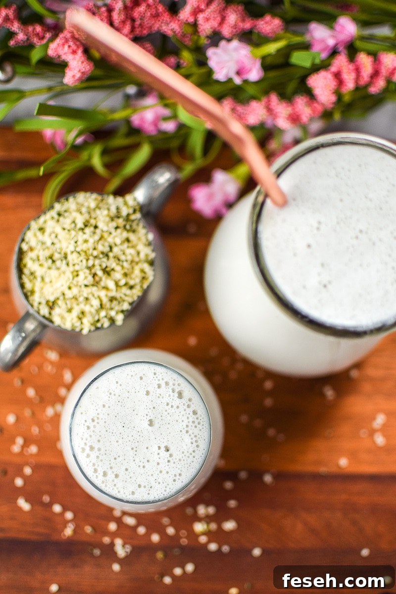 A cutting board with a cup full of hemp seeds, a carafe and a cup of homemade hempseed milk.