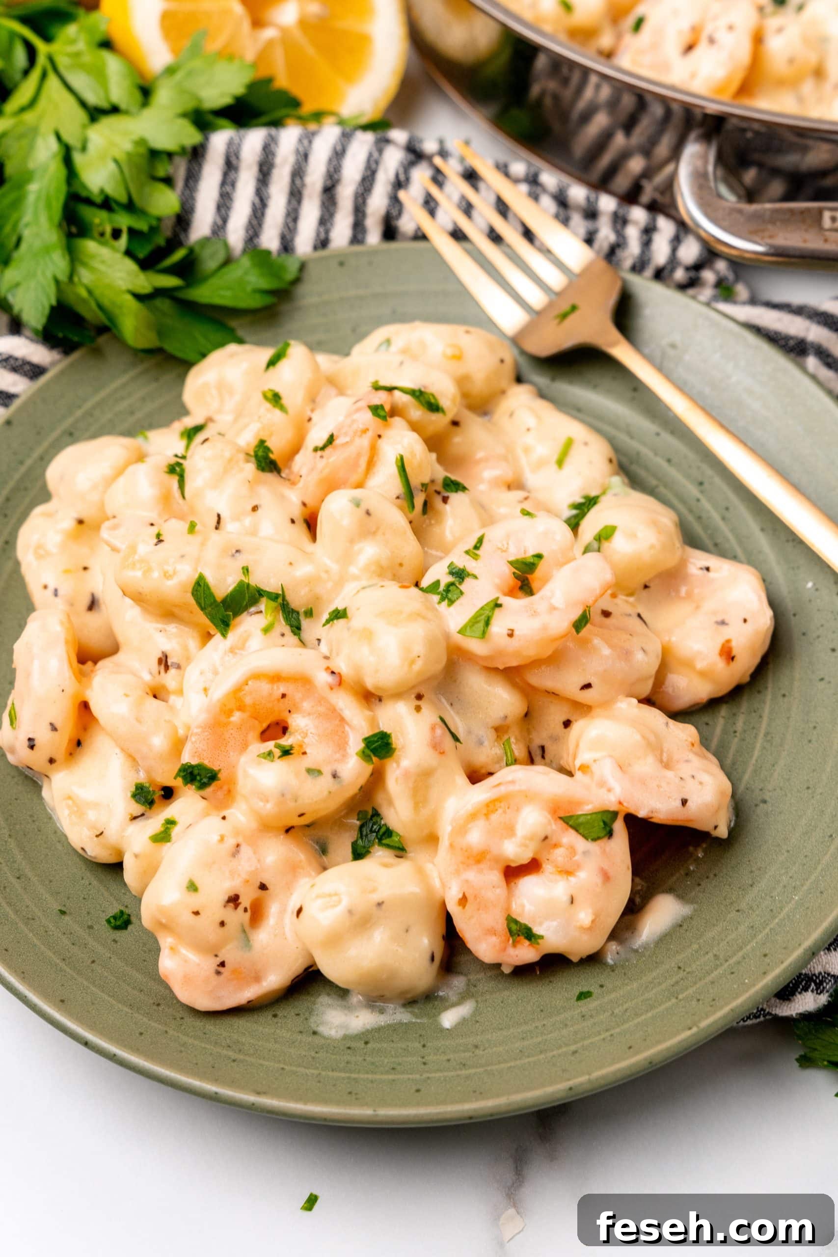 creamy shrimp scampi gnocchi on a green plate with a golden fork resting on the side