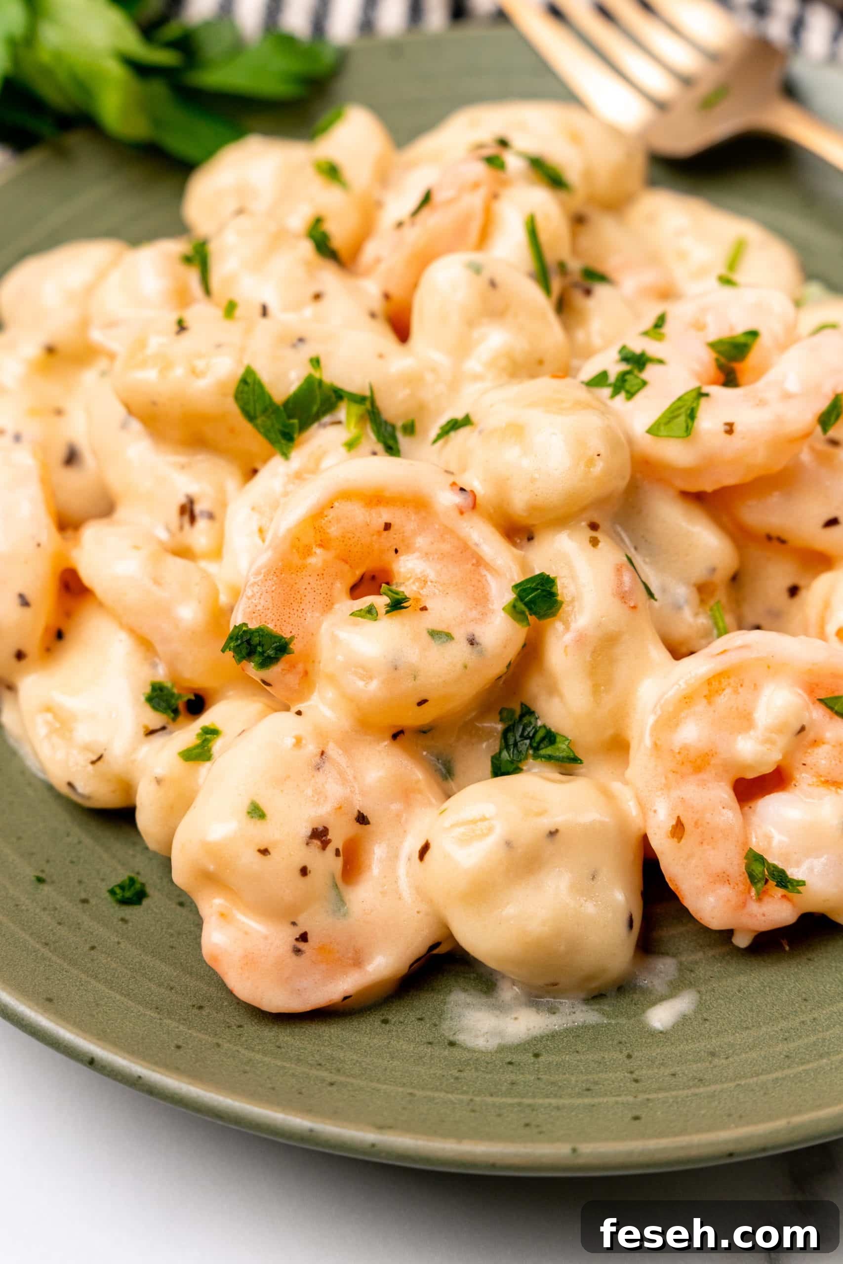 creamy shrimp scampi gnocchi on a green plate with a golden fork resting on the side