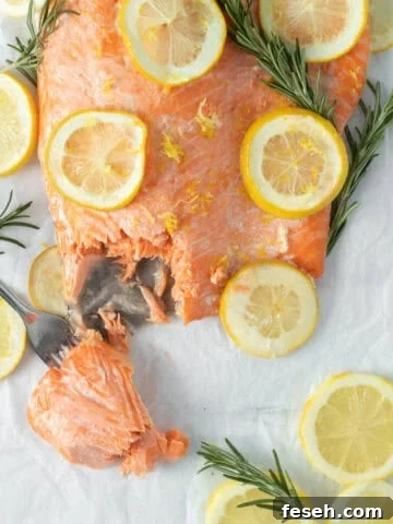 baked lemon butter salmon with lemon rounds on parchment paper.
