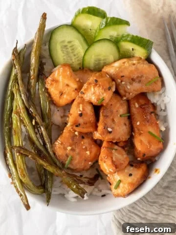salmon bites in a rice bowl with cucumber and green beans.