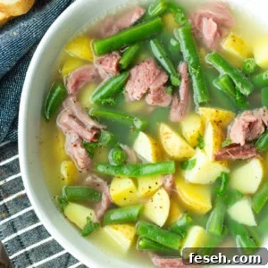 a photo of a bowl of ham hock soup loaded with potatoes, green beans and chunks of ham
