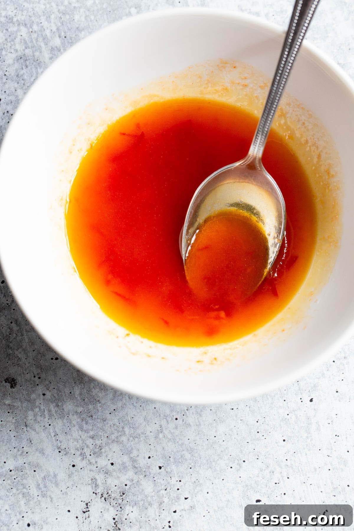 Harissa honey dressing in a bowl with a spoon.