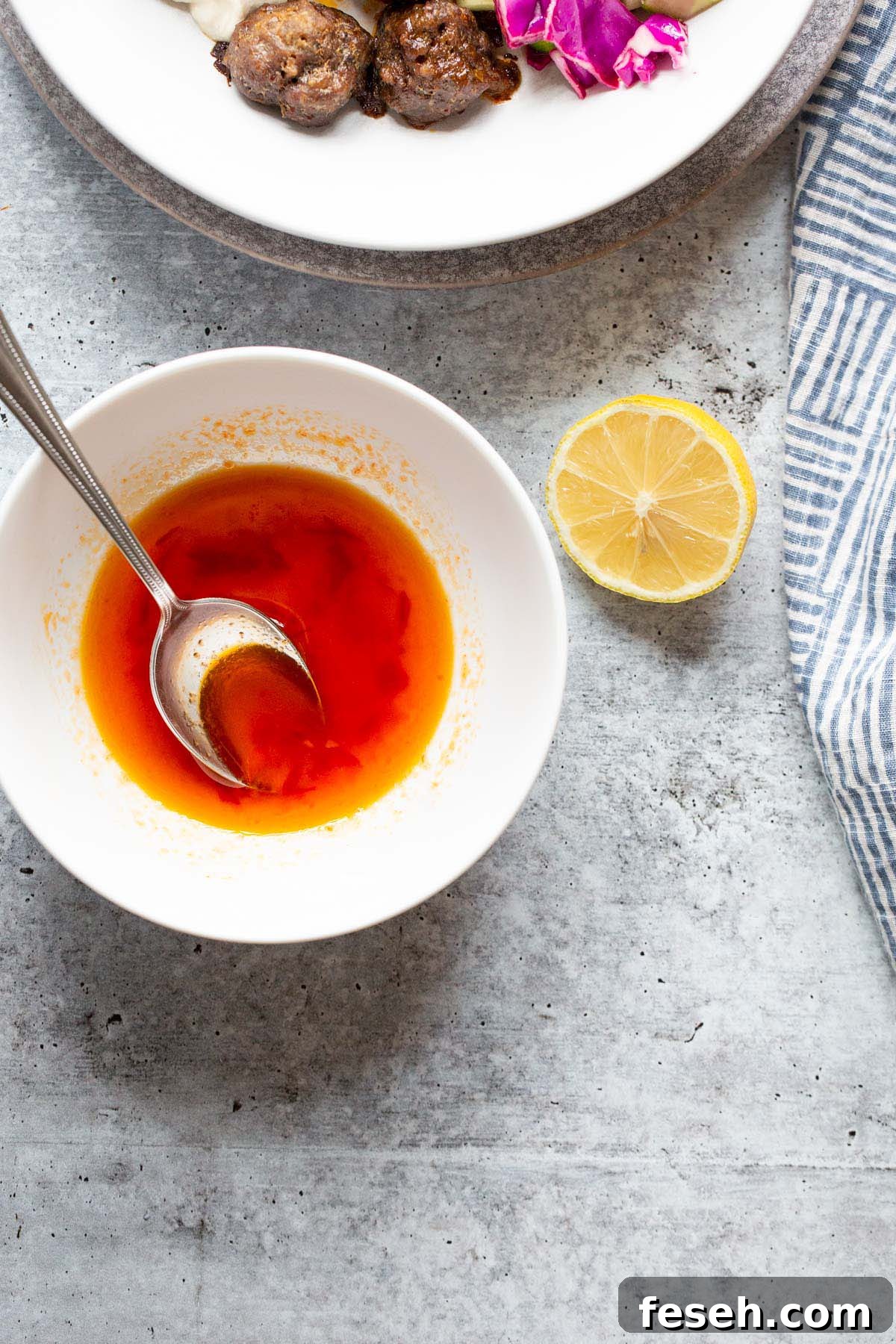 Harissa honey vinaigrette in a white bowl with lemon on the side.
