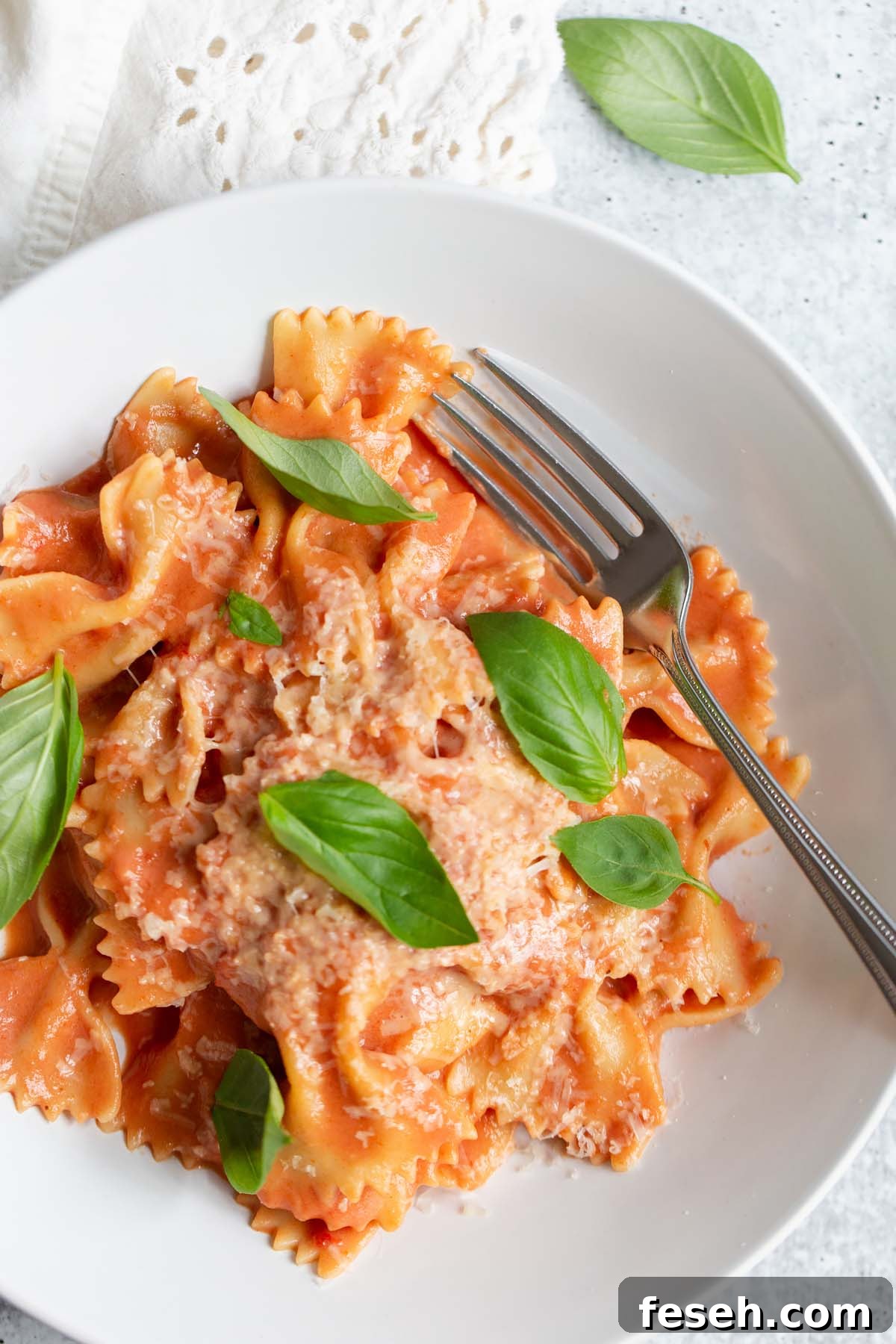creamy harissa pasta topped with fresh basil leaves