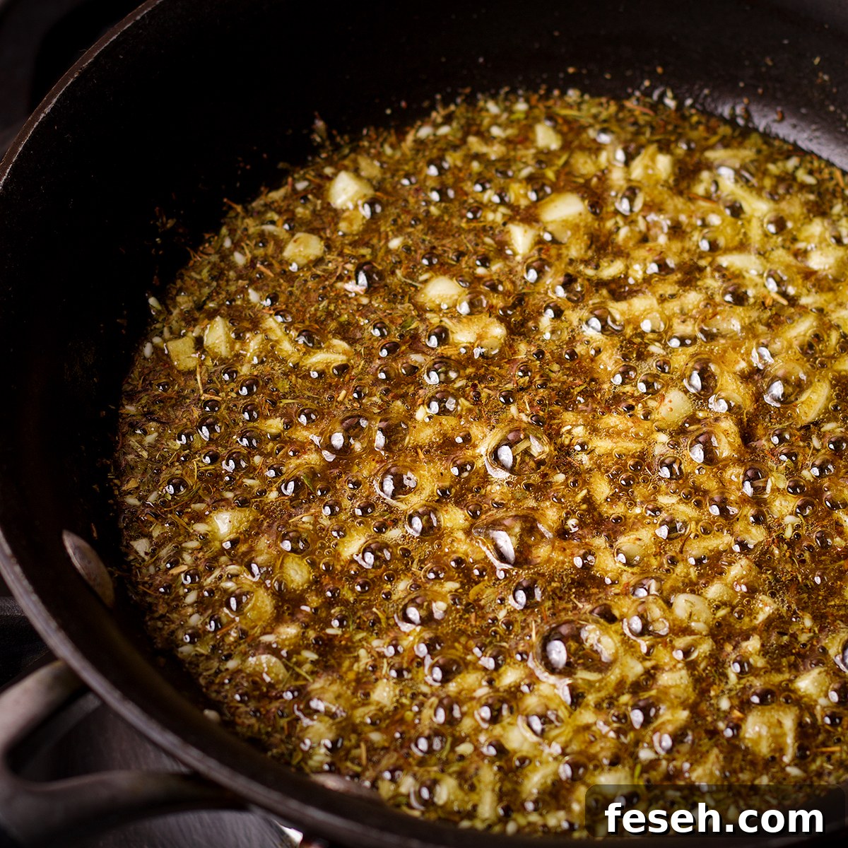 Za'atar and garlic simmering in olive oil in a black skillet.