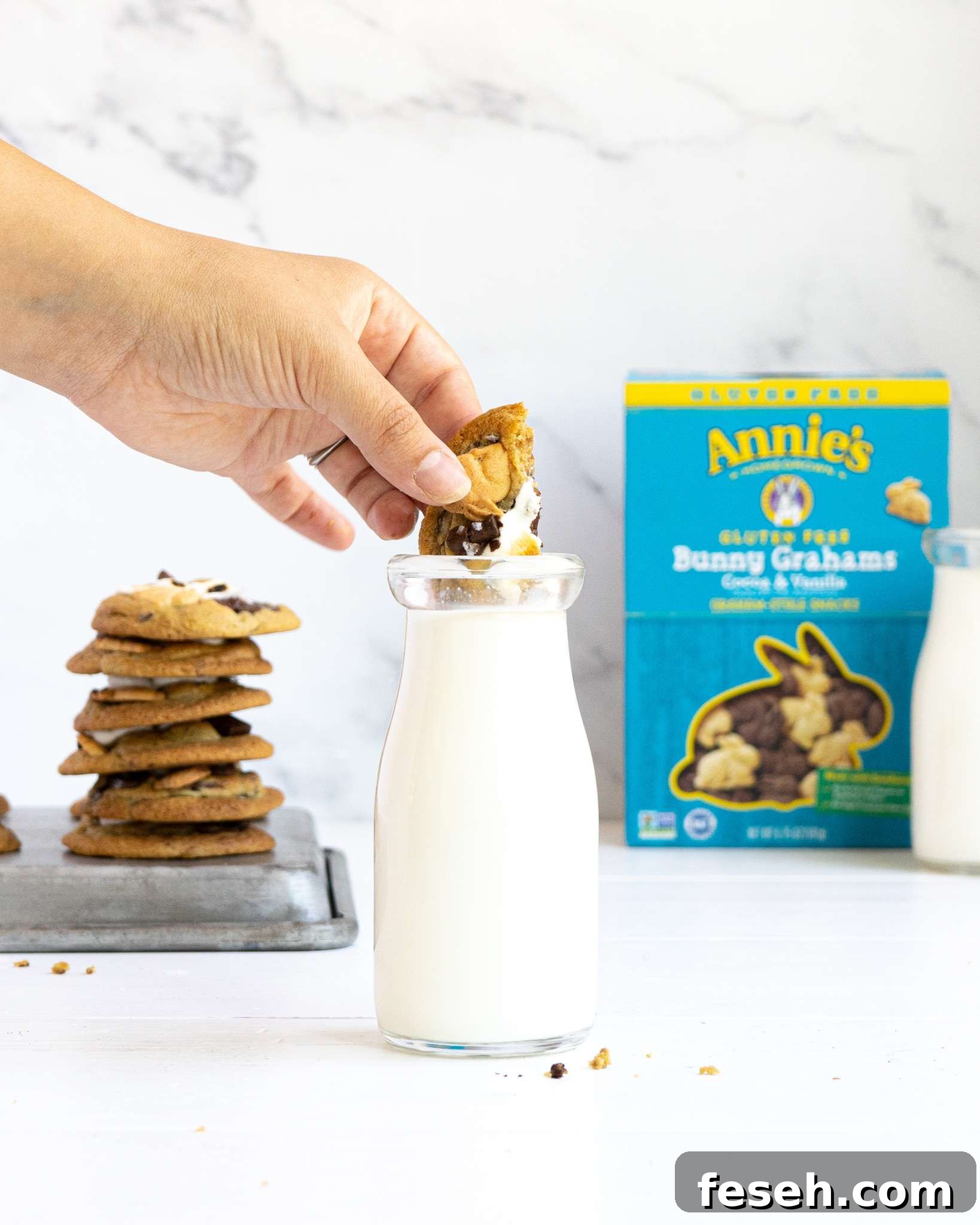 A s'mores cookie dipping into a jar of milk with an Annie's box in the background.