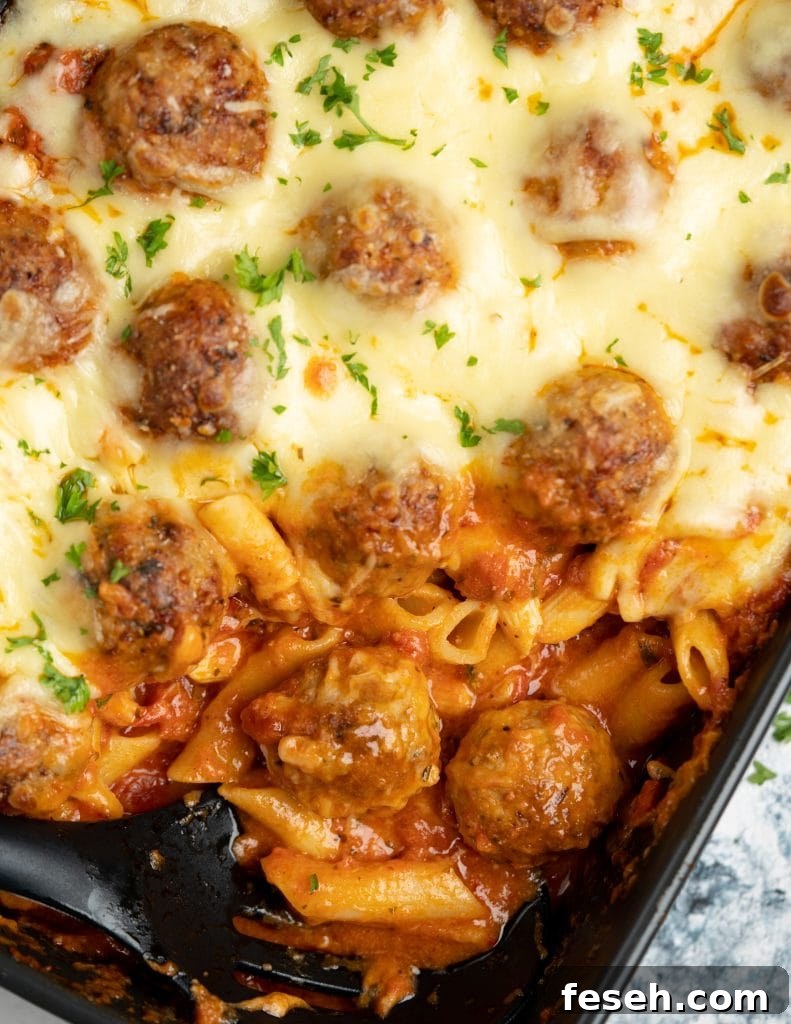Corner of meatball casserole sliced to shown saucy pasta, tender meatballs and gooey cheese
