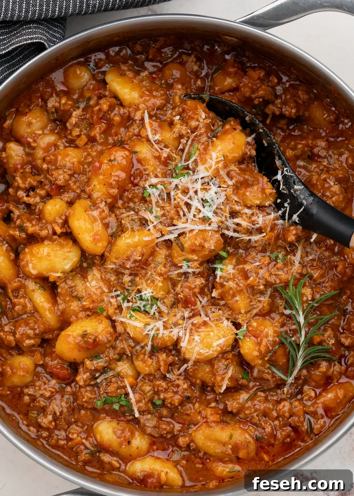 Gnocchi Bolognese in a serving dish, garnished with grated parmesan and chopped parsley. 